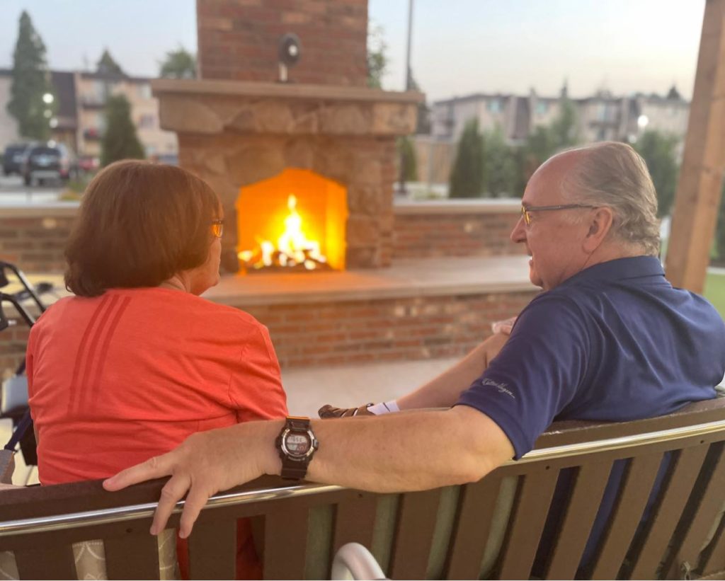 Couple sitting in front of outside courtyard fireplace
