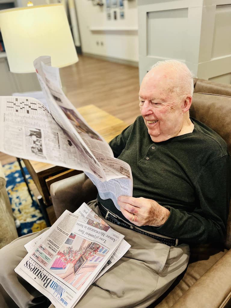 Senior man sitting in chair and reading a newspaper